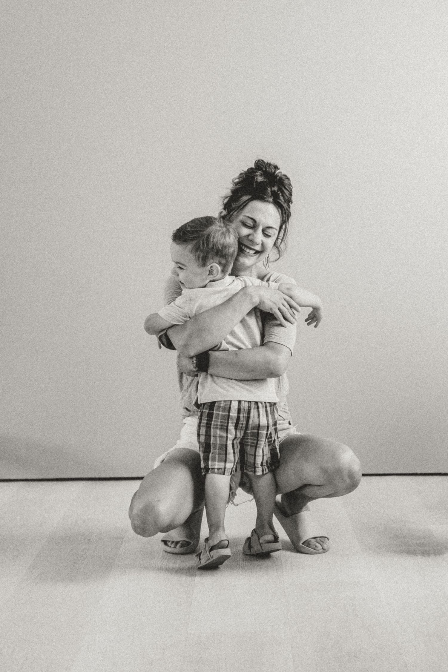 A black and white photo series showing two children embracing and hugging in different poses on a light background.