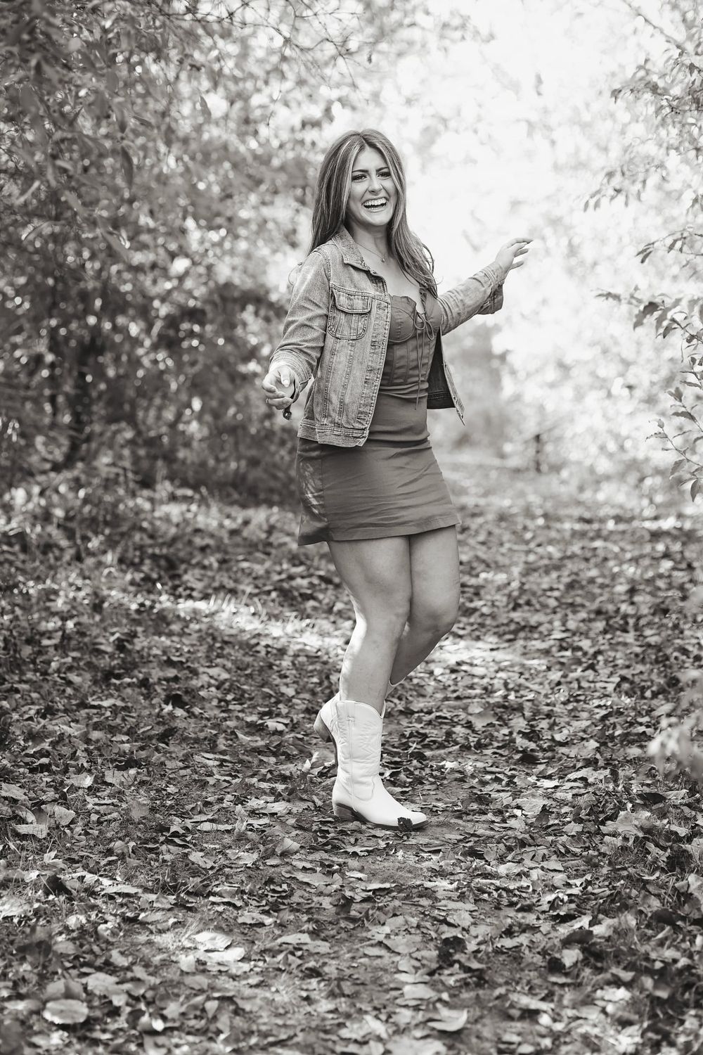 Playful black and white portraits on fallen leaves wearing casual denim and boots.