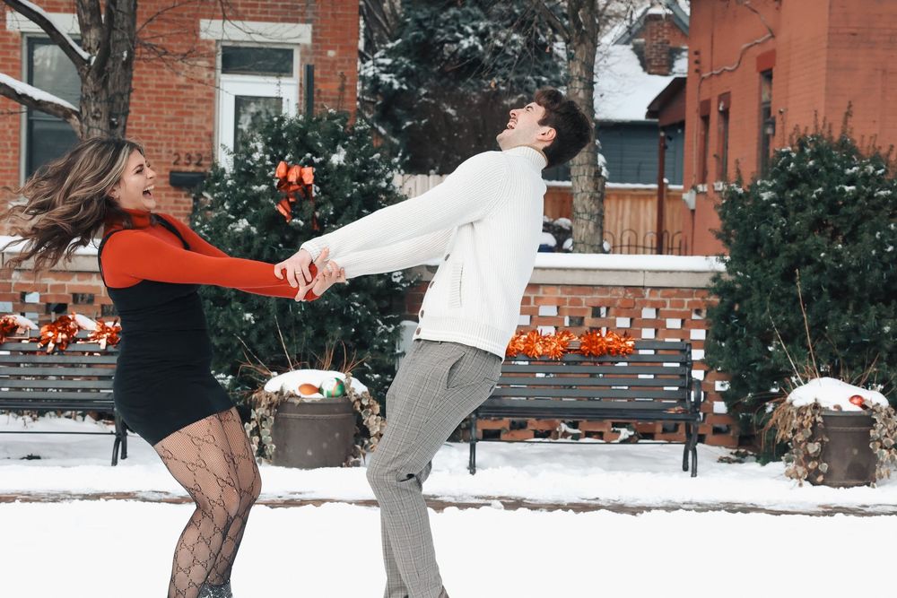 Playful winter photoshoot with couple having fun in snowy outdoor setting.