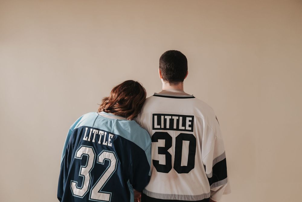 Couple wearing matching hockey jerseys with numbers 32 and 30 photographed from behind.