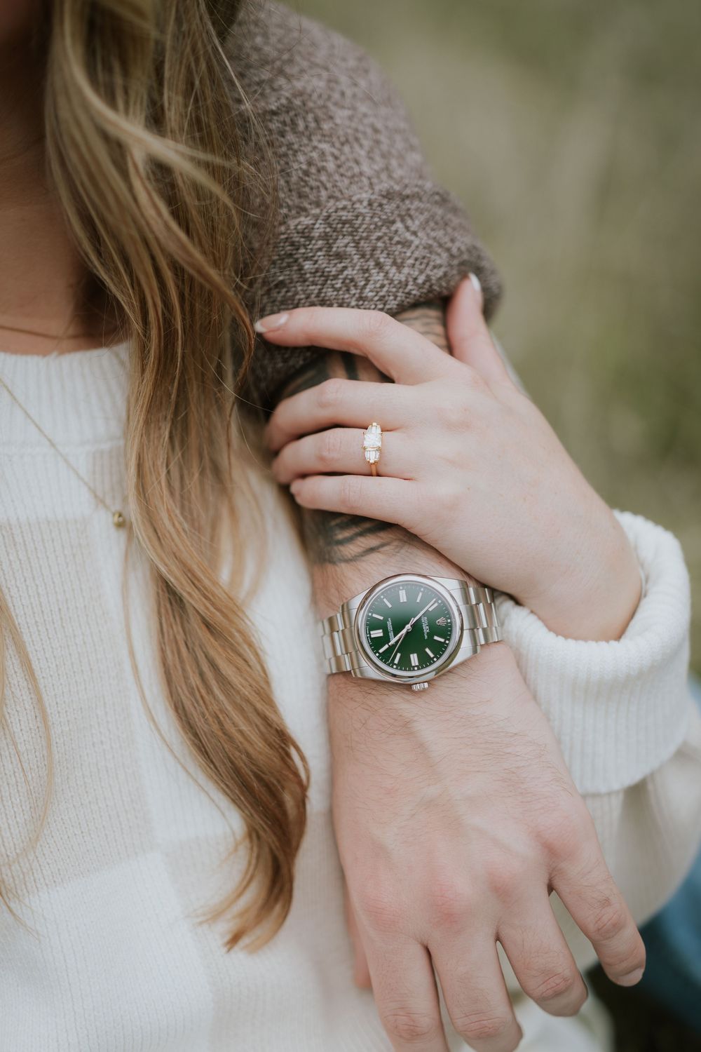 Close-up shots of hands wearing a white sweater and silver watch against a blurred green background.