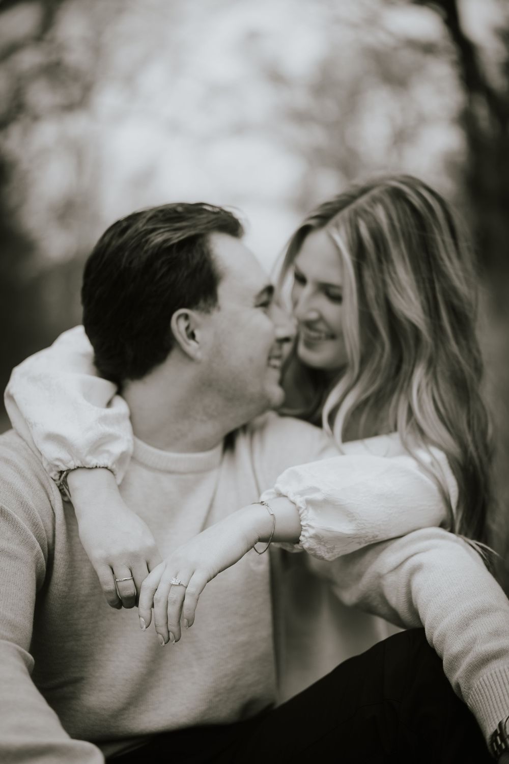 Black and white romantic photo series showing a couple in white sweaters sharing intimate moments and kisses.