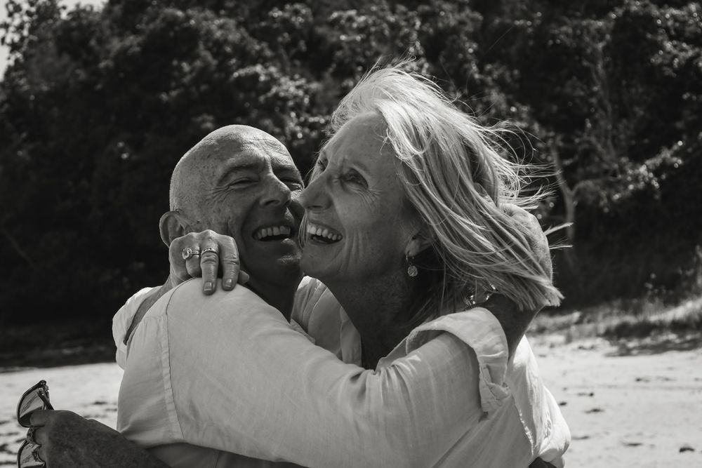 A series of black and white romantic photographs showing a couple embracing and laughing together on a beach.