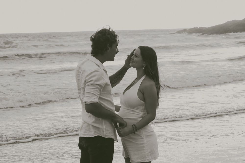 A couple embraces on the beach in a series of black and white romantic photographs.