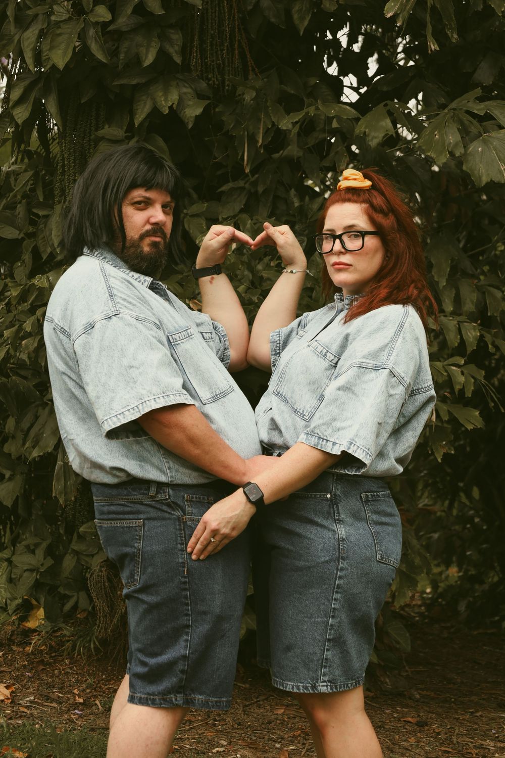 A series of five intimate poses showing a couple in matching denim outfits against a leafy backdrop.