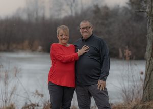 Family wearing red and black outfits poses together in outdoor winter setting with bare trees in background.