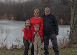 Small group poses together by a lake wearing casual winter clothing on an overcast day.