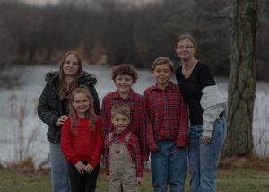 A family portrait taken outdoors with children and adults arranged in front of a lake.