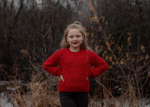 People in red sweaters and casual attire stand together against natural winter landscape backdrop.