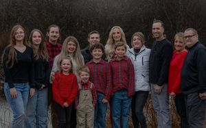 Extended family group portrait outdoors with multiple generations wearing coordinated casual clothing.