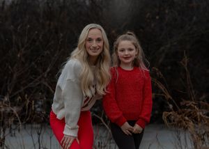 Two people in winter sweaters pose together outdoors against a moody winter backdrop.