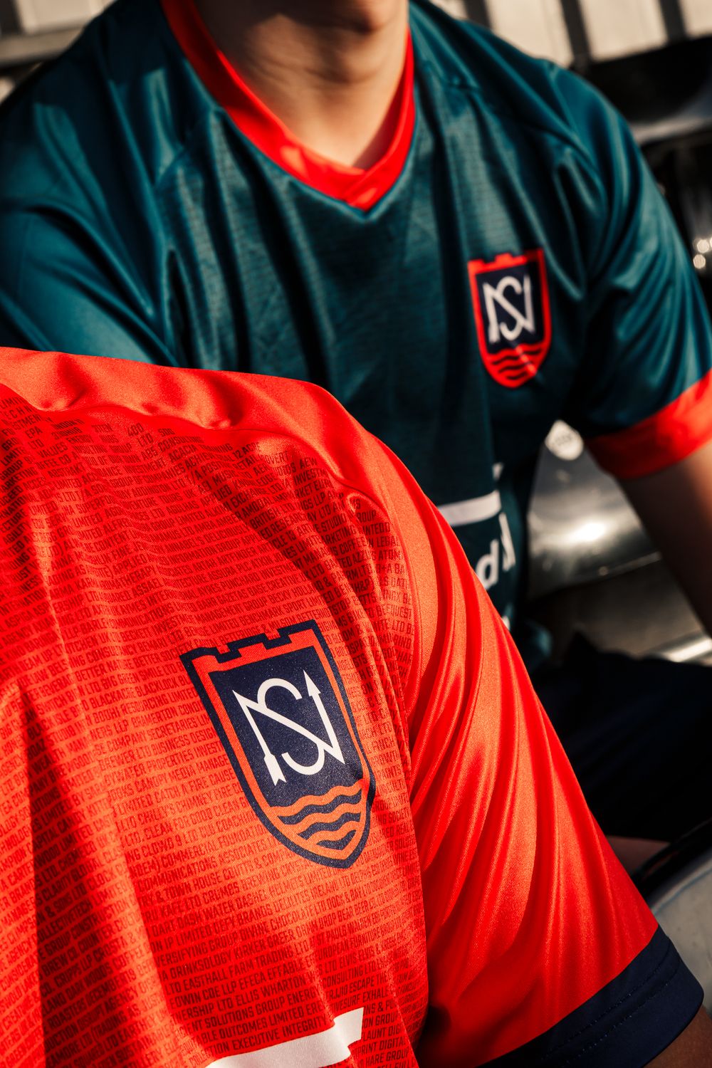 Close-up shots of a red and navy blue sports jersey with NSI logo and textured fabric pattern detail.