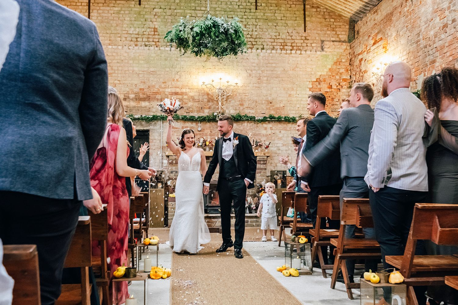 The Oakley Barn - Wedding guests seated in wooden pews react emotionally during a ceremony in an indoor venue.