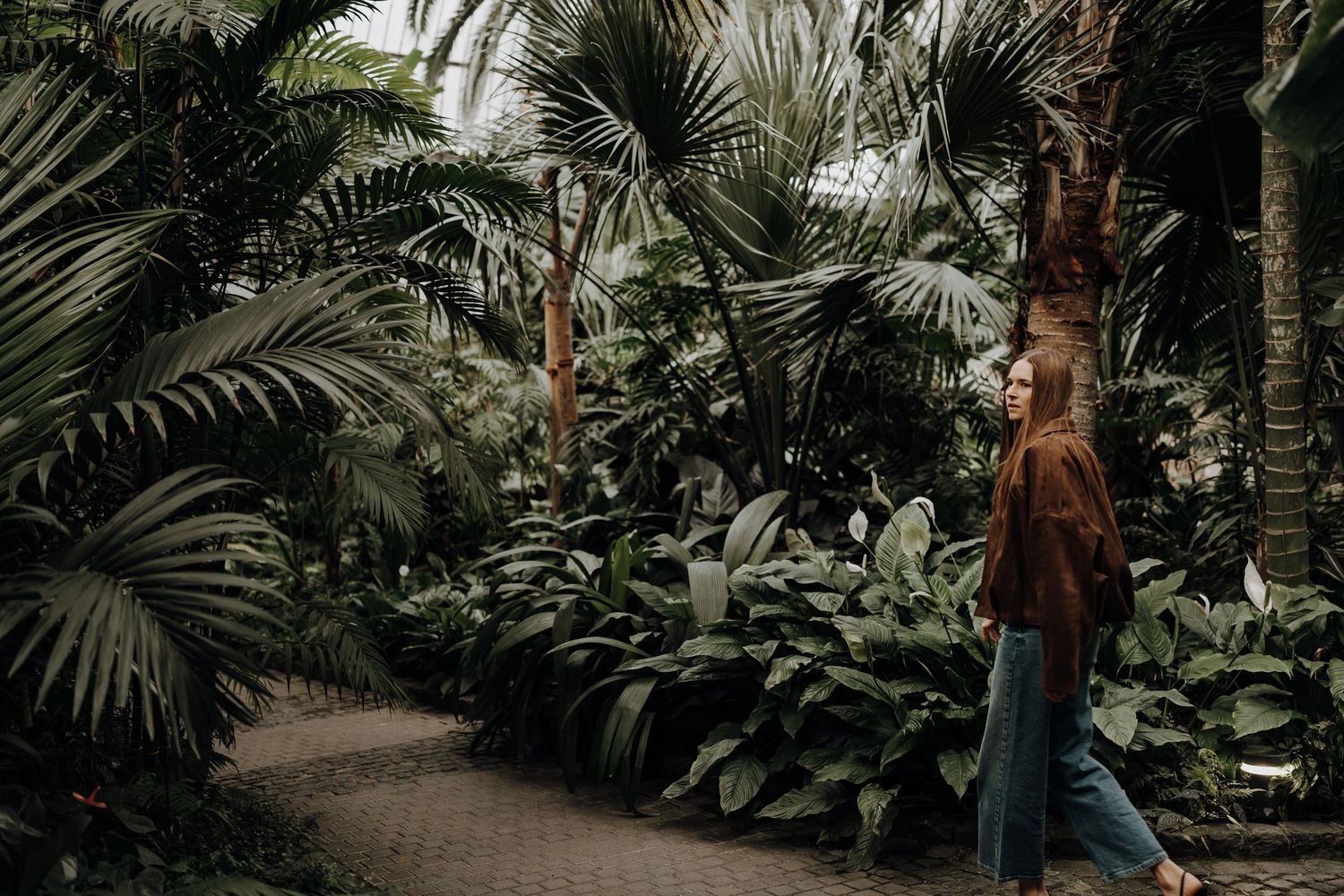 Frau läuft durch einen Palmengarten.