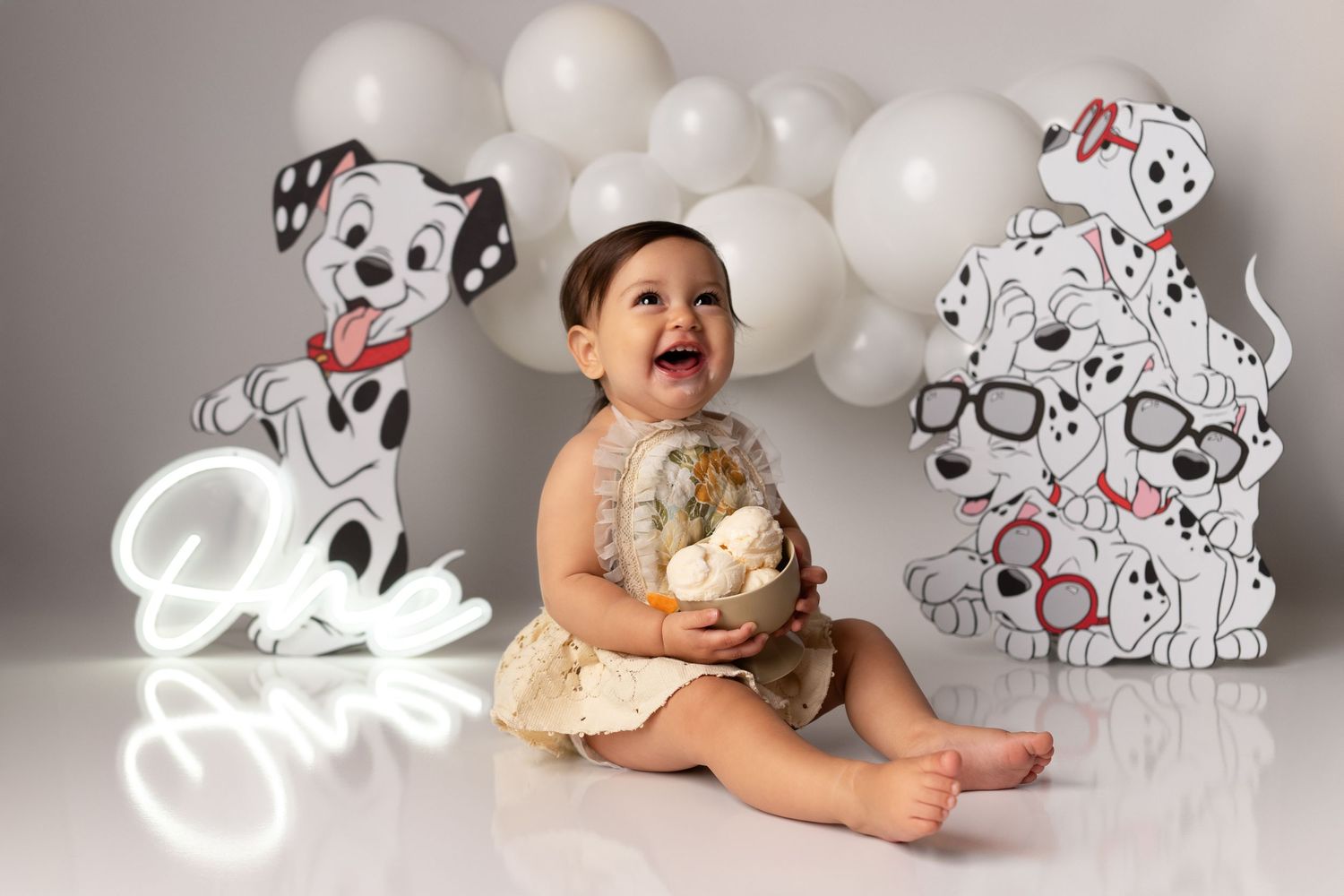 Adorable Dalmatian-themed first birthday photo shoot with white balloons and spotted puppy decorations.