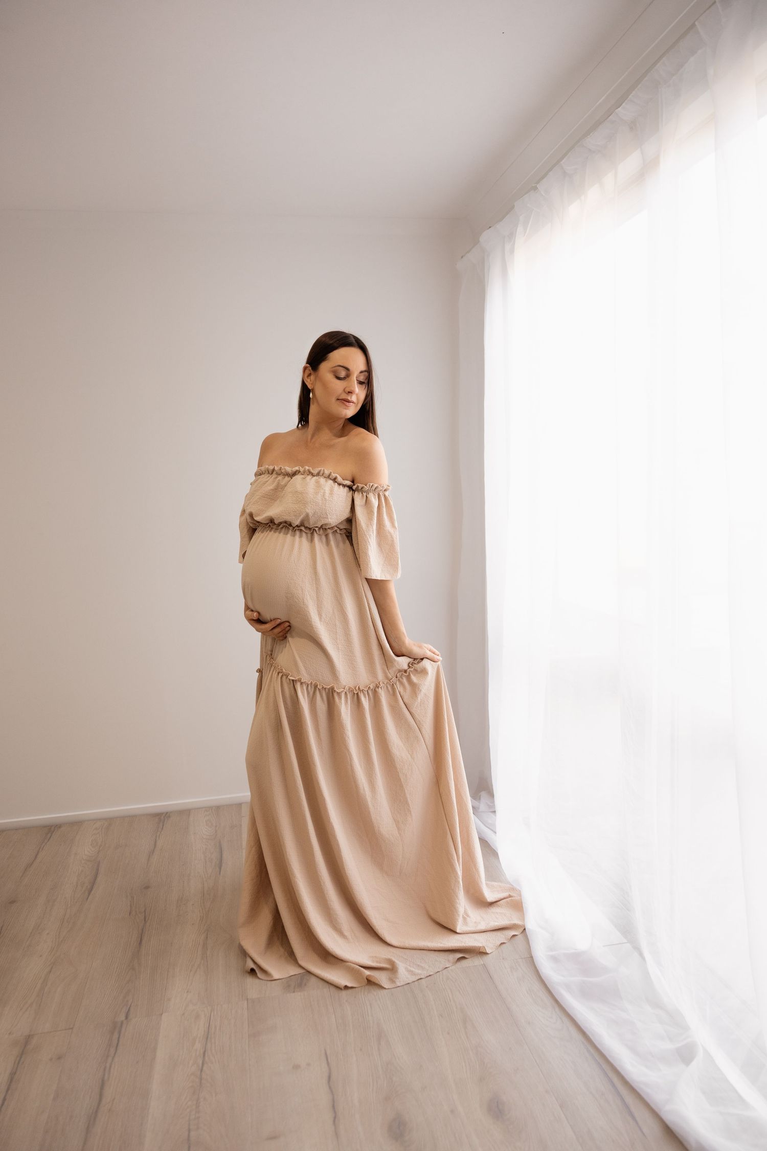 Pregnant mother in the water holding her baby bump during maternity photoshoot