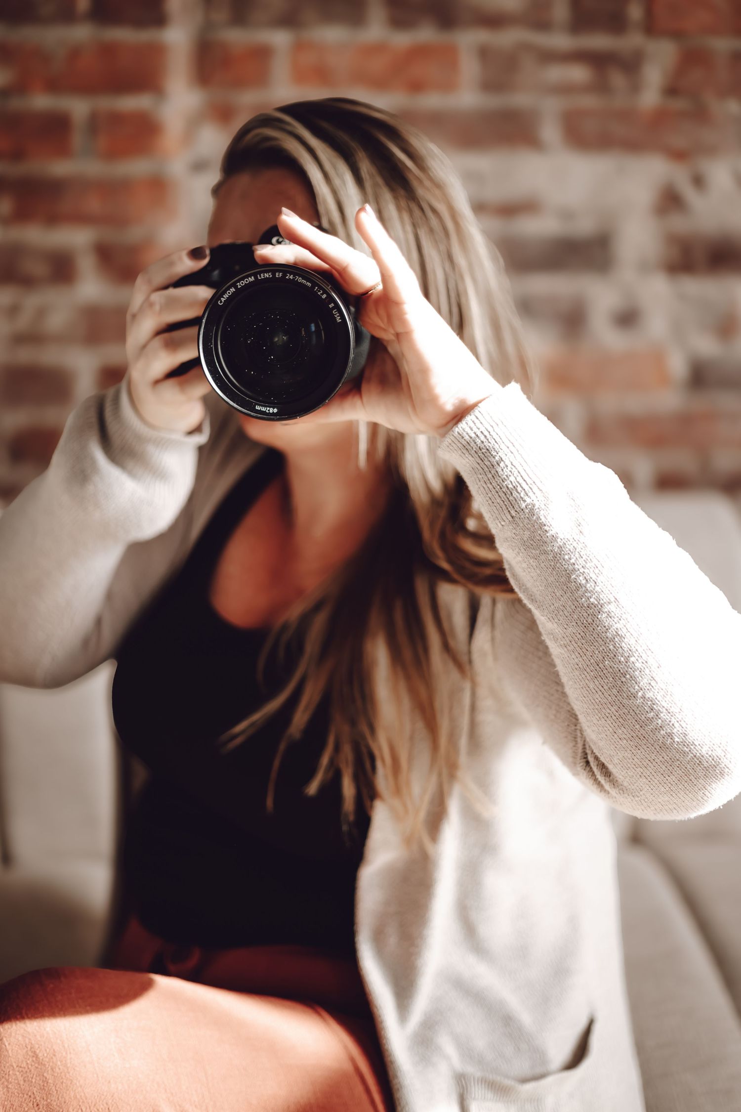 Photographer sitting in front of brick wall holding camera in new castle, Indiana.
