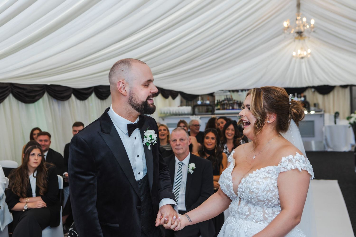 Emotional wedding ceremony moment captured in an elegant white draped marquee.