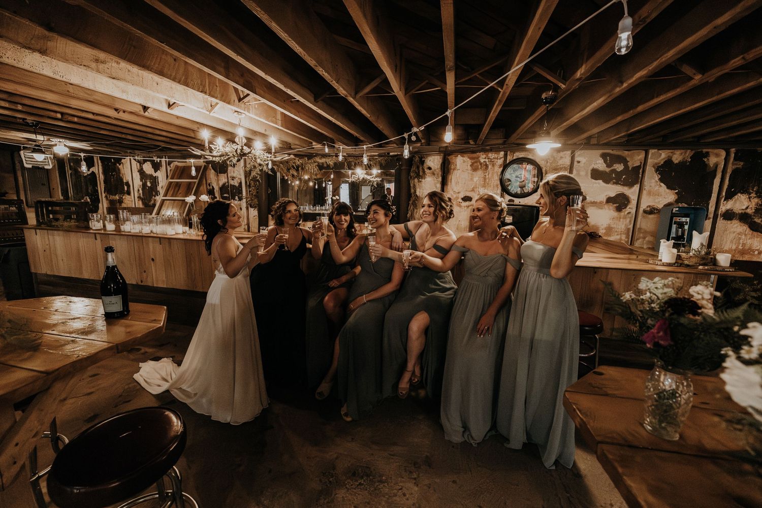 Wedding party gathered in rustic basement venue with exposed beams and vintage decor.