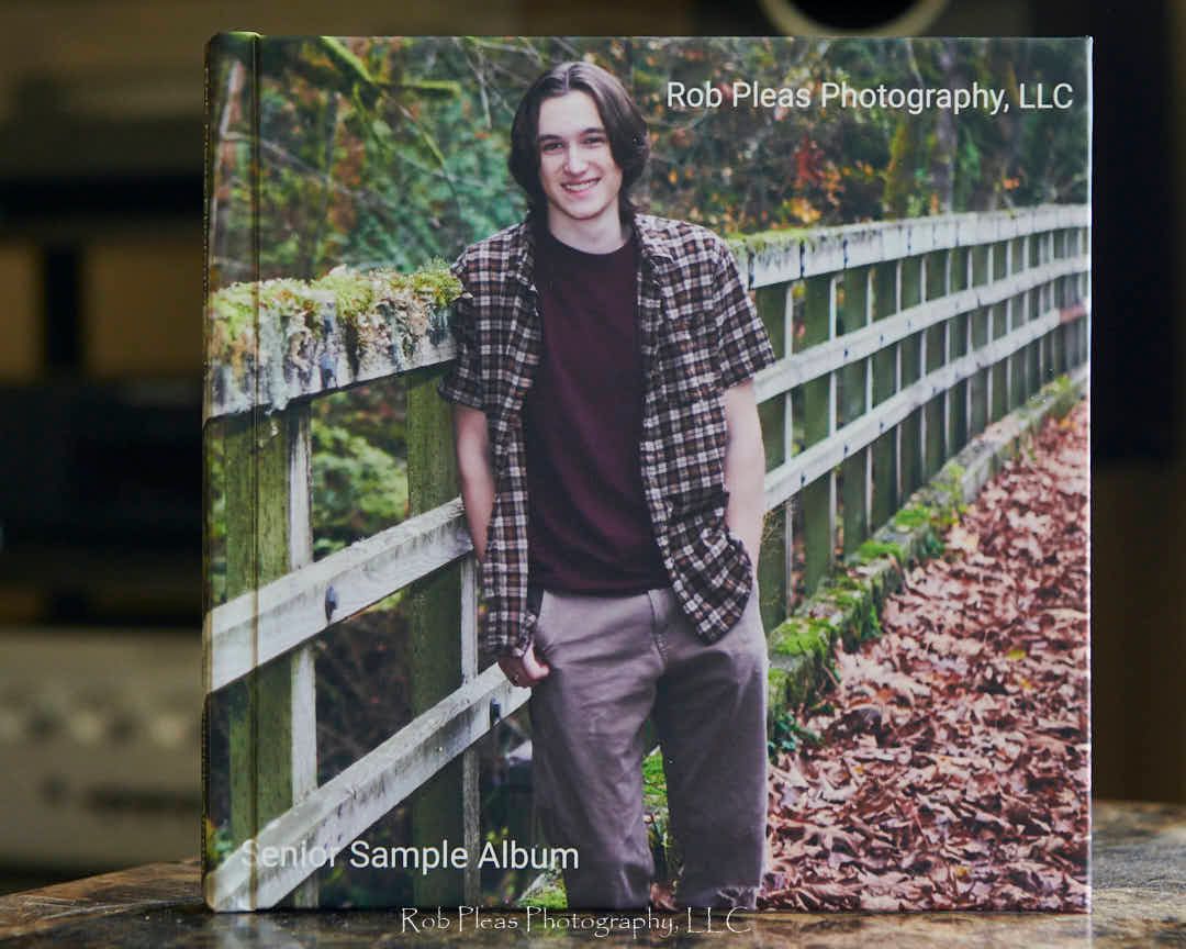 Example of senior photo album with cover photo.  Male senior in the fall leaning against a wooden fence.
