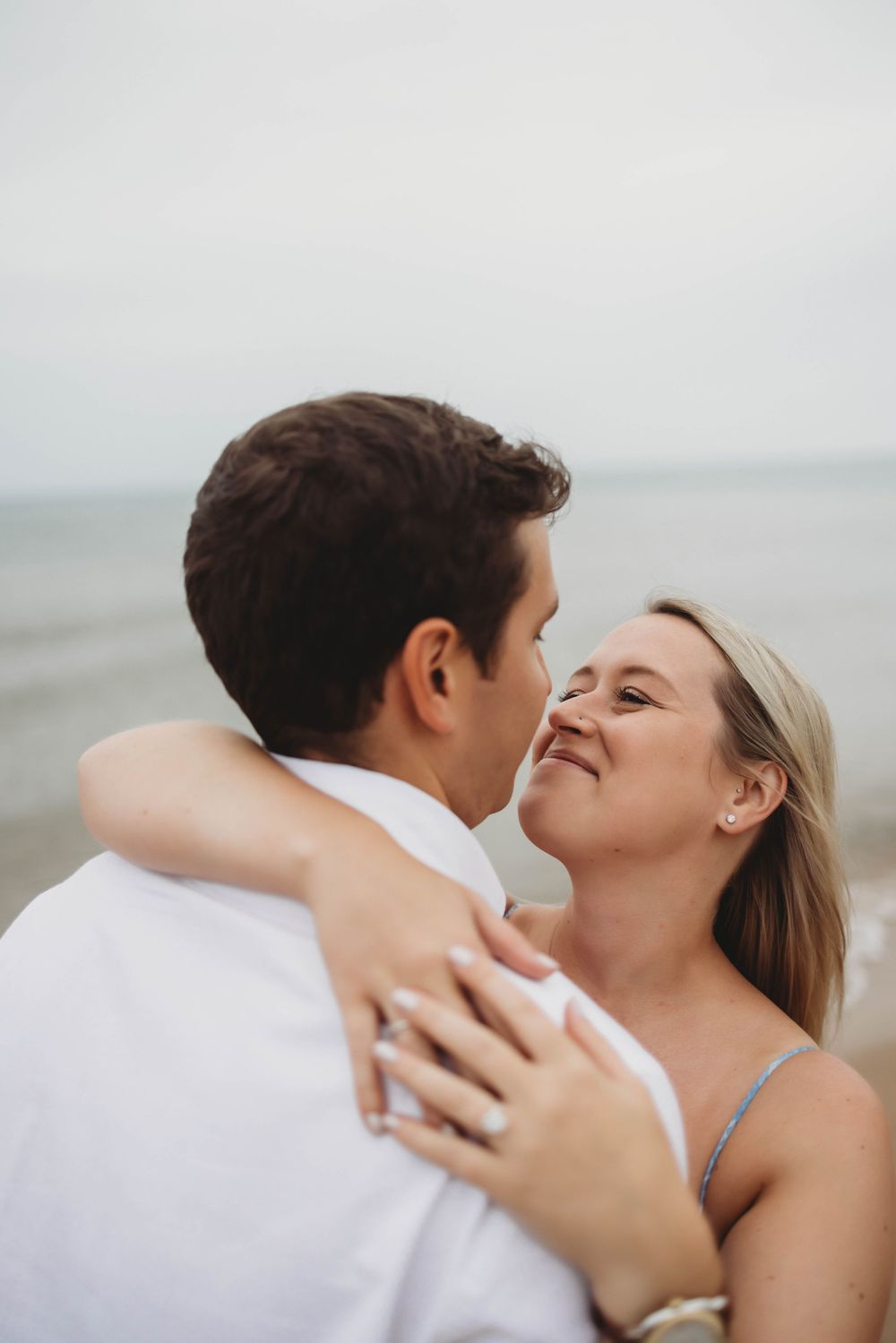 A tender romantic moment shared between a couple at the beach with soft lighting.