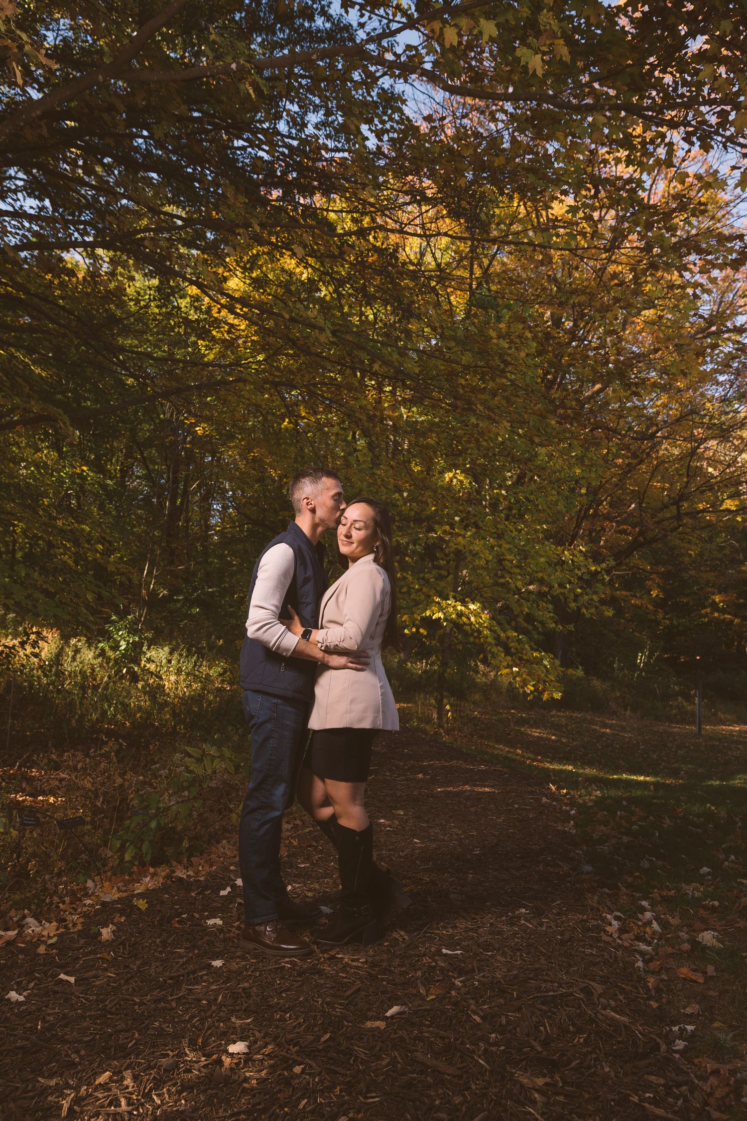 Couple enjoying an autumn day together on a wooded hillside with golden leaves.