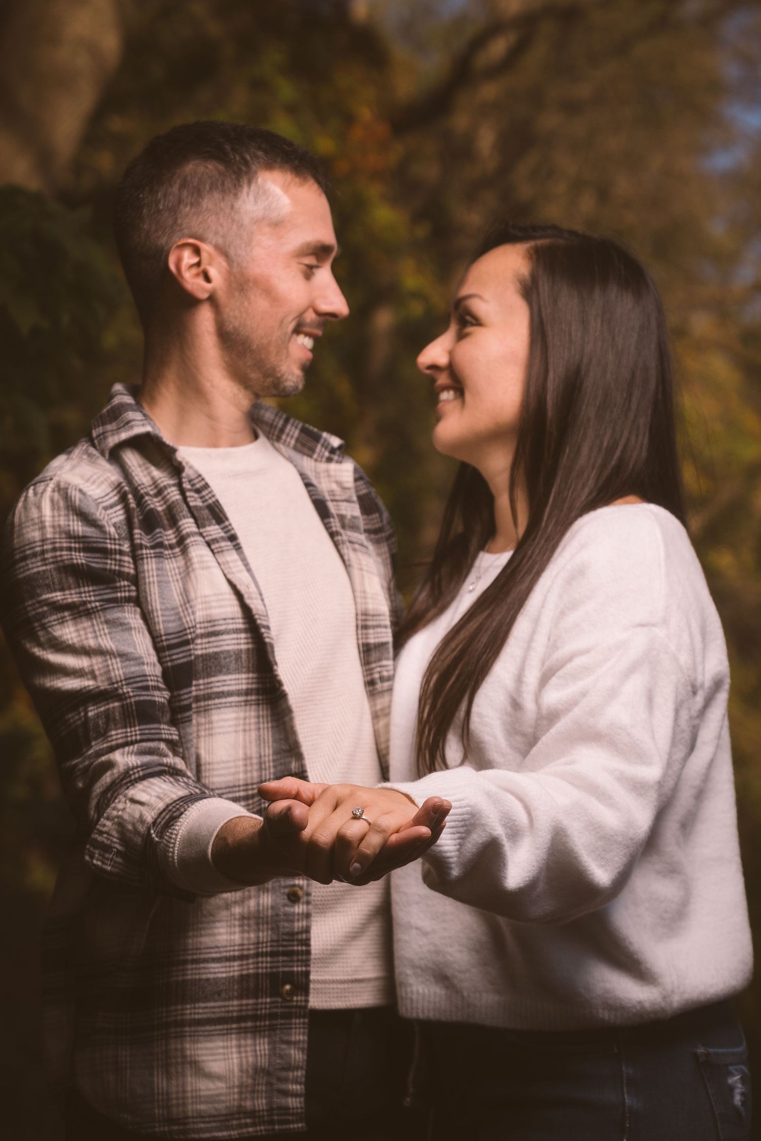 Couple in matching white sweaters sharing playful moments in an autumn setting.
