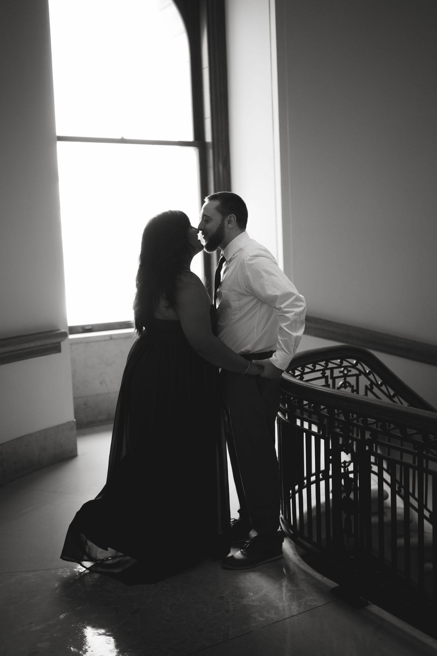 Romantic couple embracing on vintage staircase in black and white.