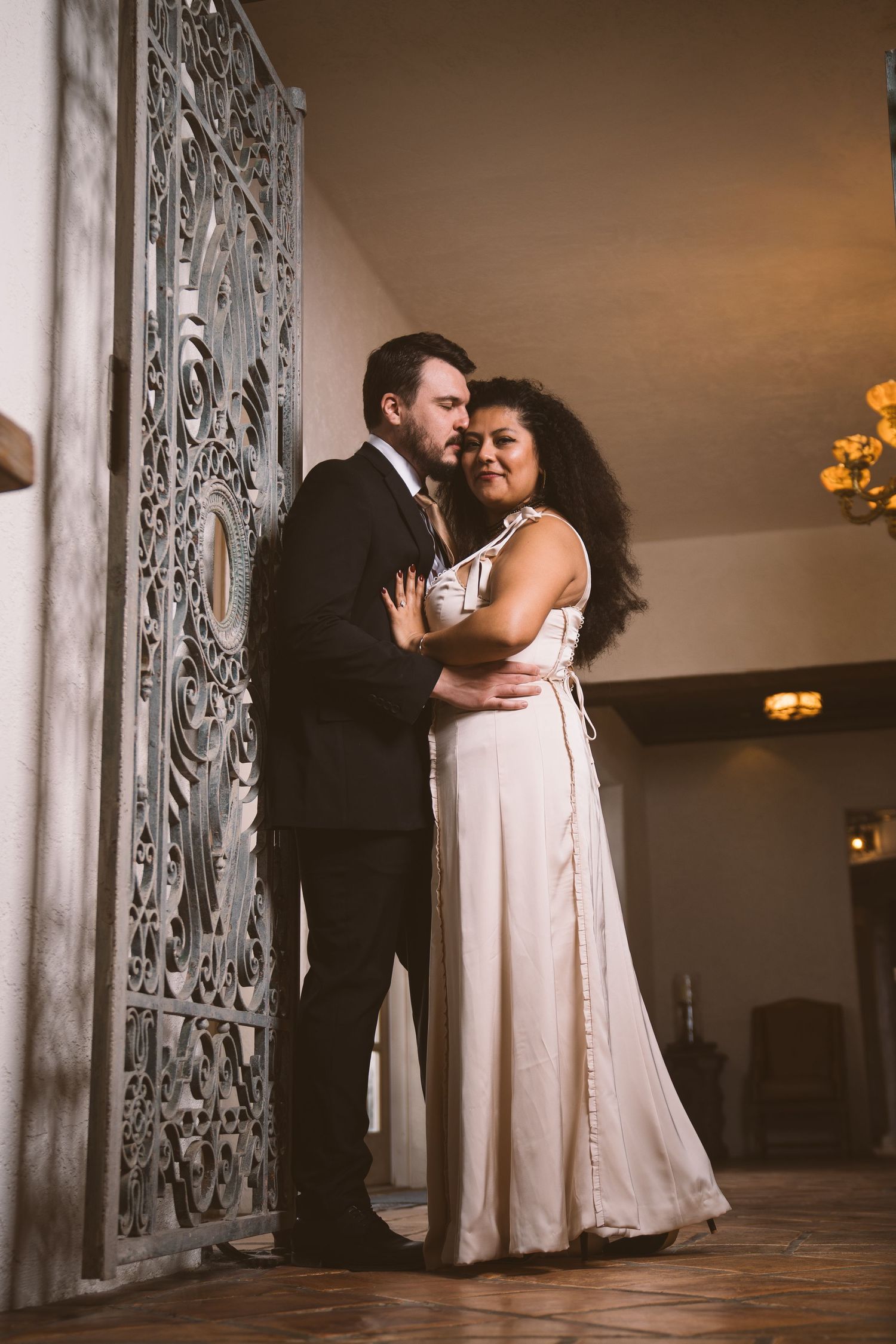 A couple shares an intimate dance moment in front of an ornate white wall.