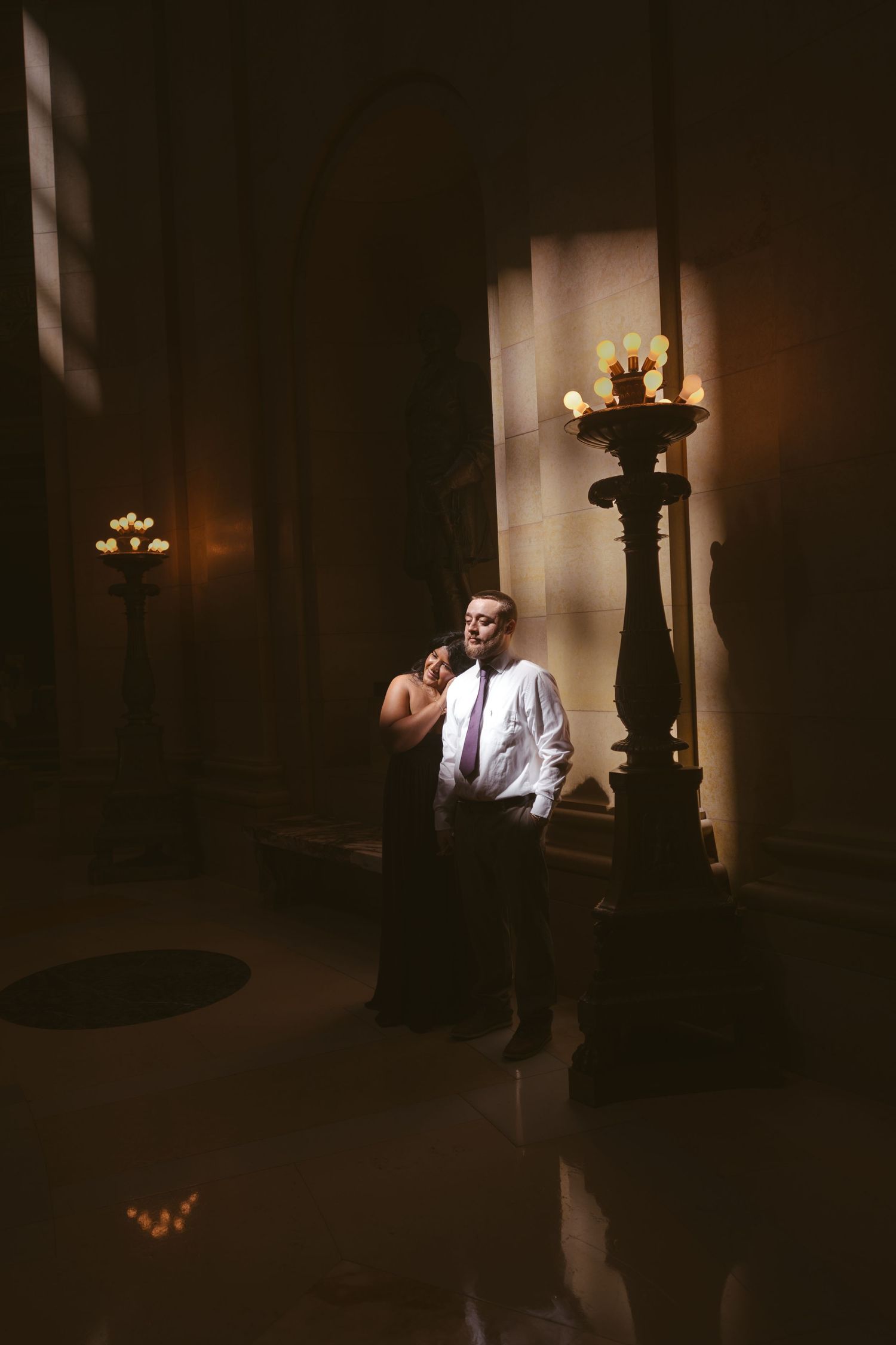 Dramatic shadows frame a tender moment between two people in formal wear.