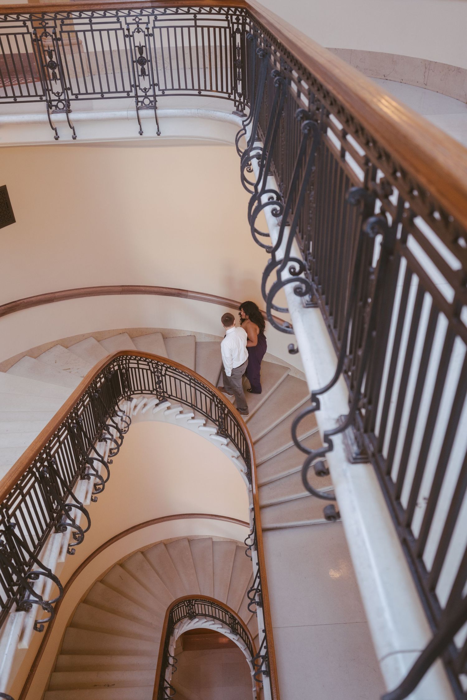 An elegant spiral staircase with ornate iron railings and wooden handrails.