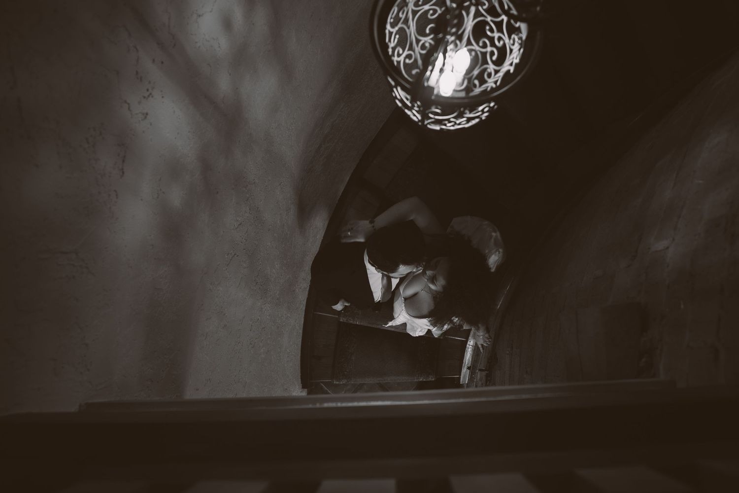 A dramatic low-light portrait in a dark atmospheric setting with vintage architectural details.