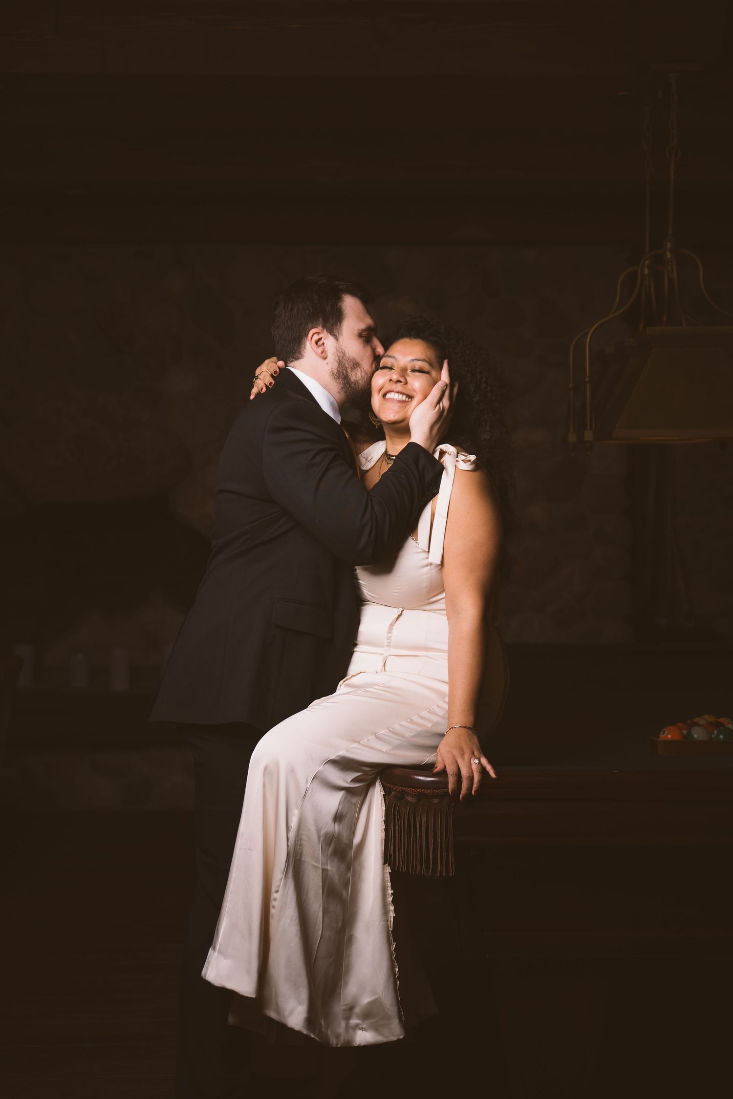 A couple shares an intimate moment in a dark, moody setting.