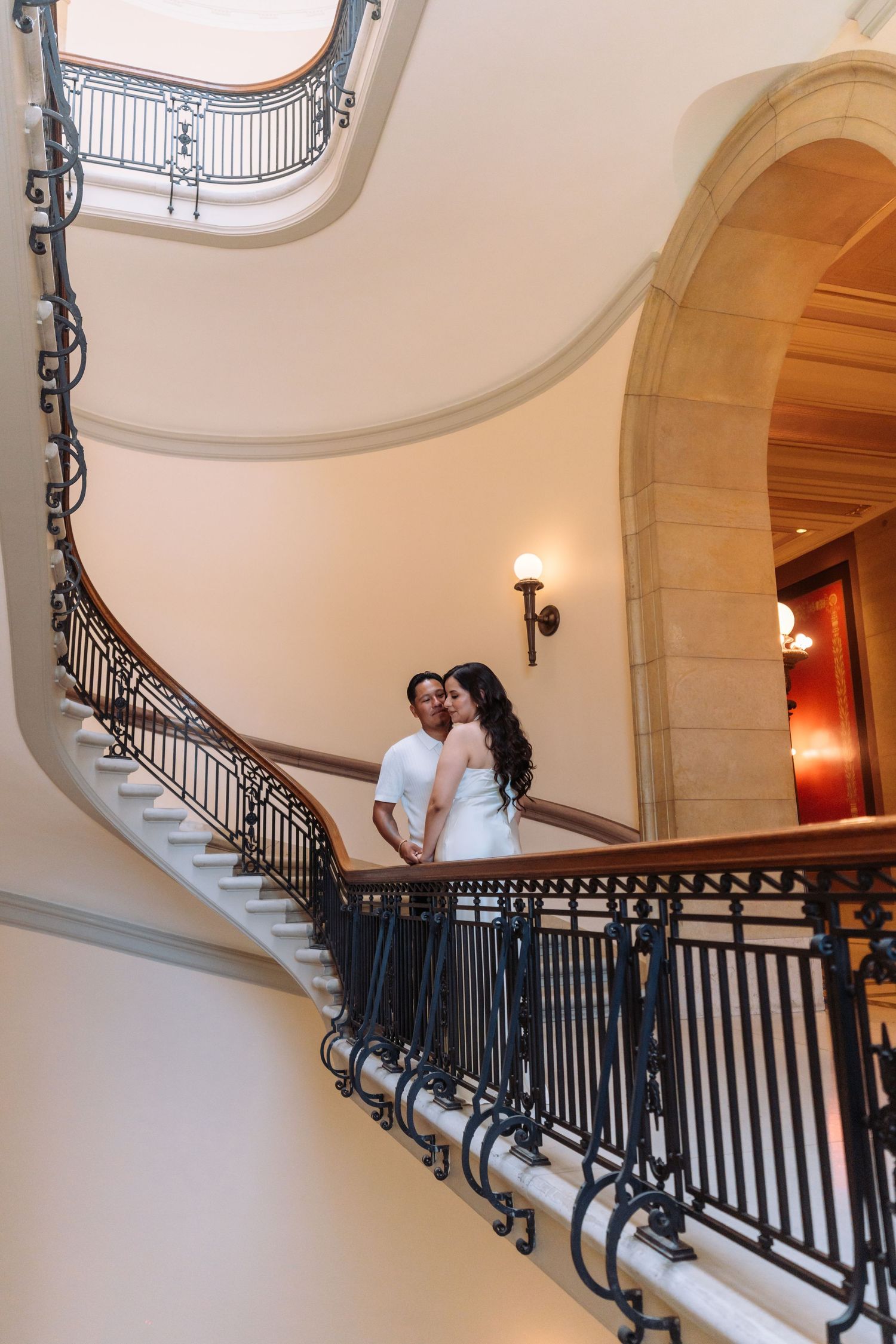 Elegant architectural staircase frames a romantic moment between two people.