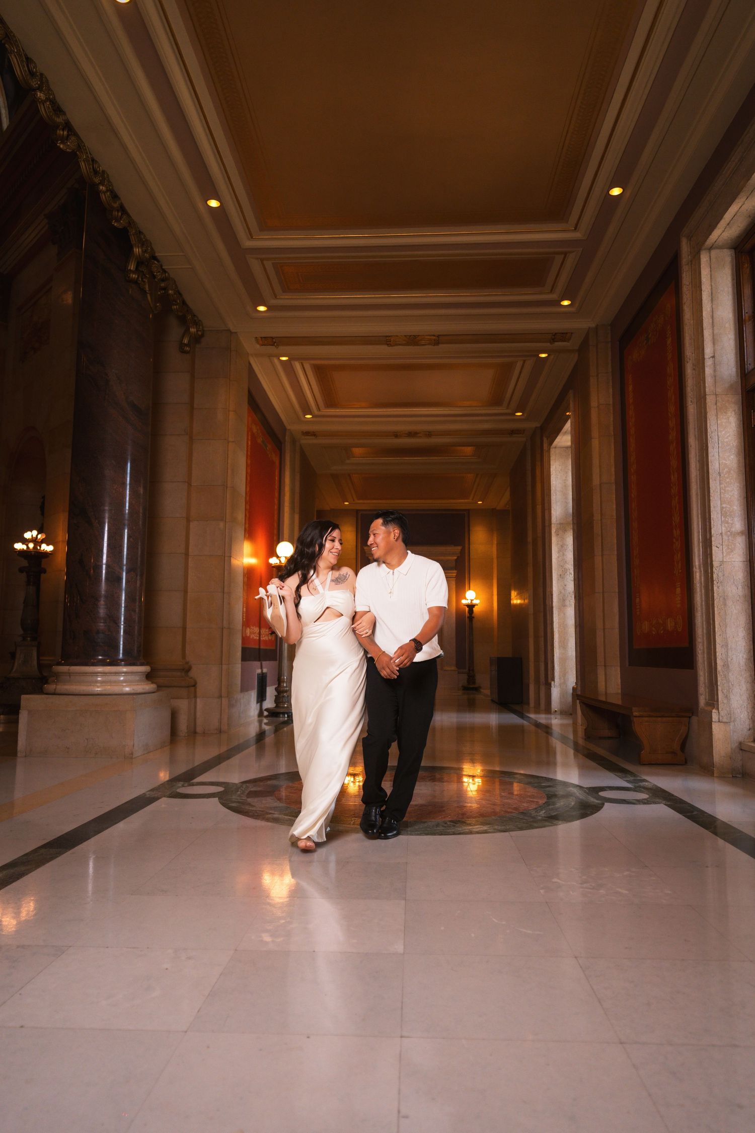 Dancing couple spins across polished marble floor in elegant hallway with columns.