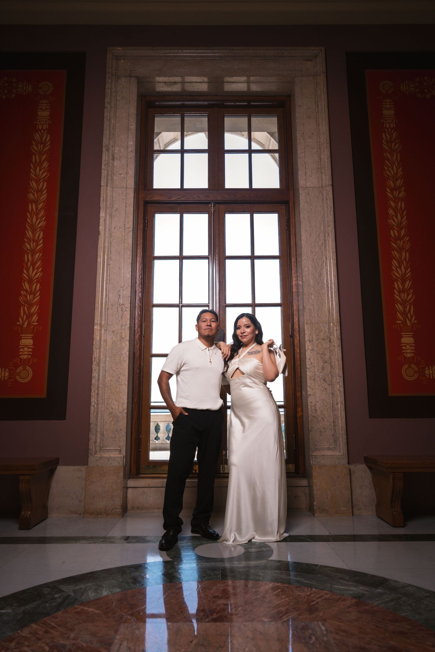 Couple dances in ornate room with tall windows and decorative wall panels.