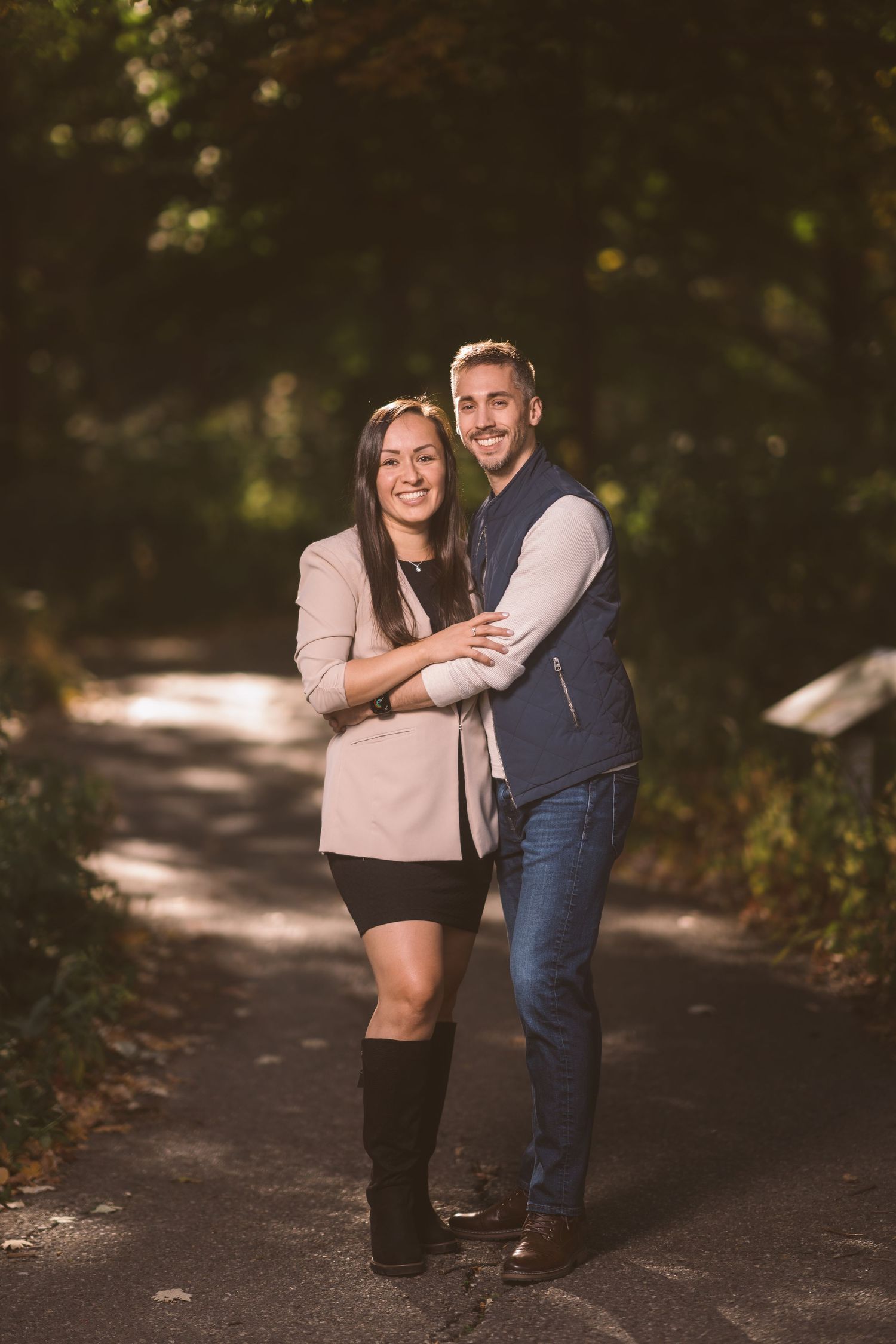 Couple walking and laughing together on a sunlit autumn path.
