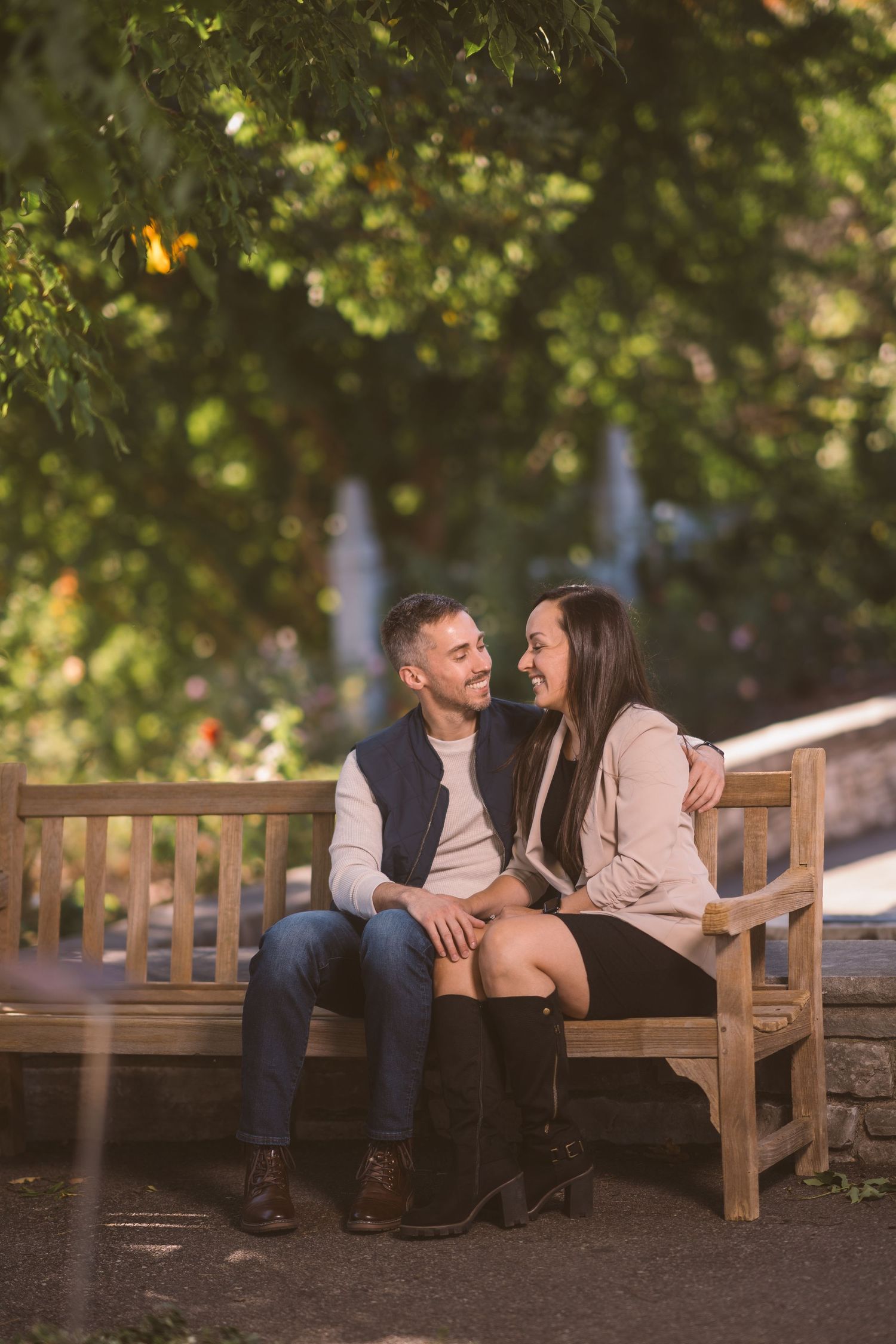Couple sharing tender moments while sitting on a wooden park bench surrounded by autumn foliage.