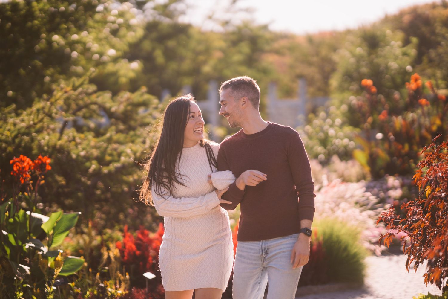 Couple walking together through a garden path during golden hour.