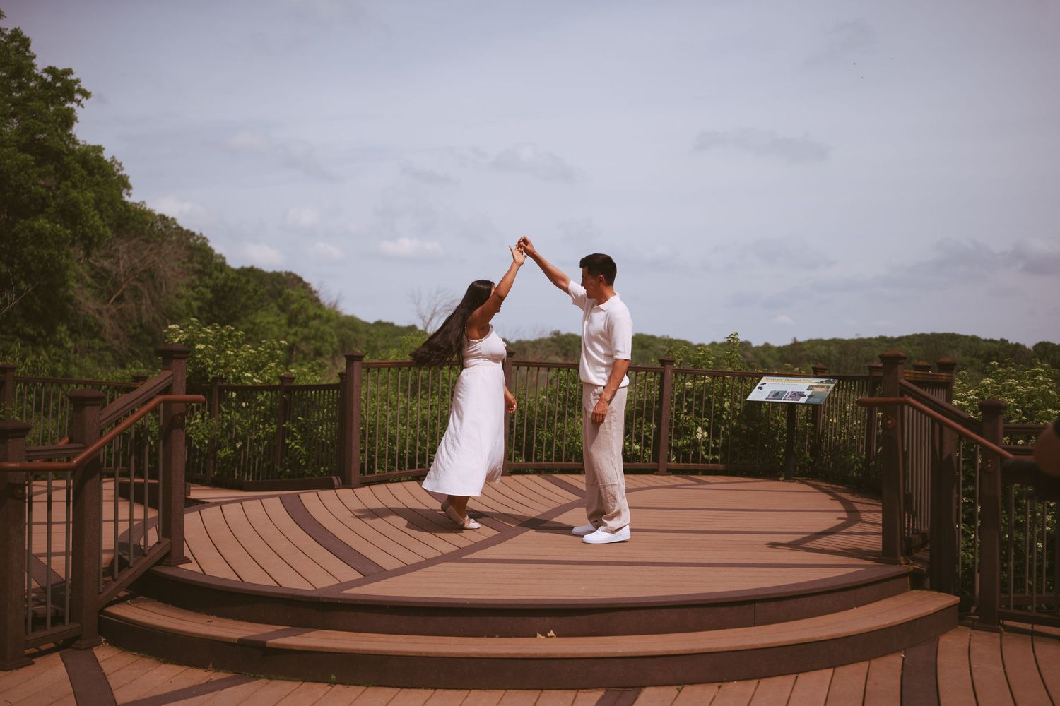 Happy couple dancing together on a wooden deck overlook surrounded by tropical greenery.