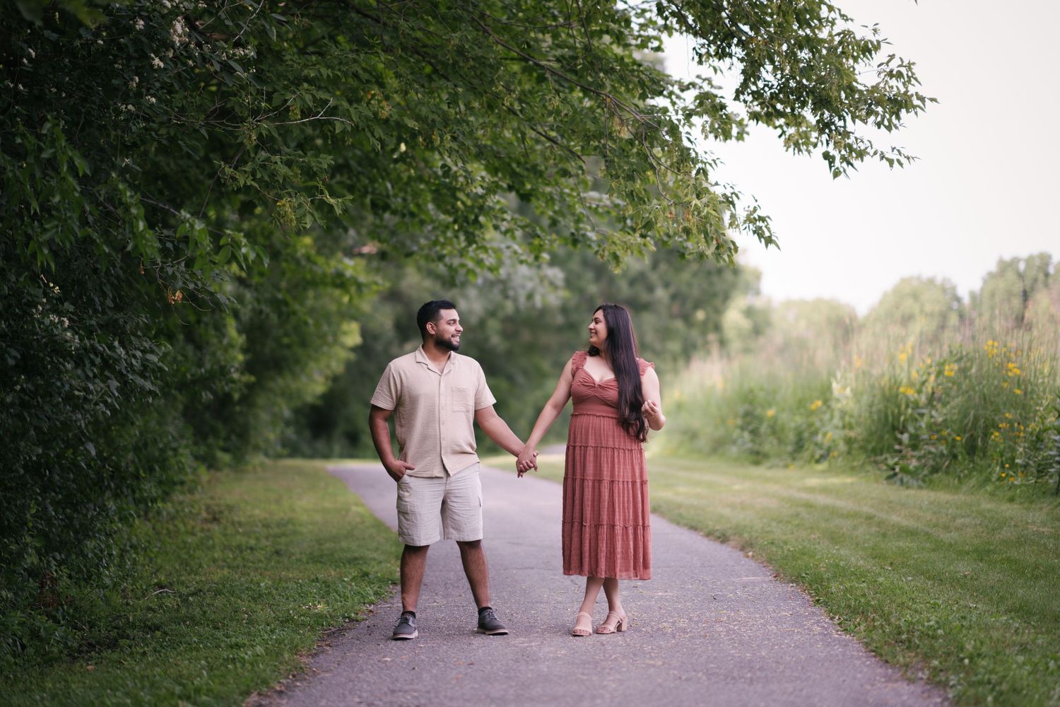A couple walks hand in hand along a scenic nature path.