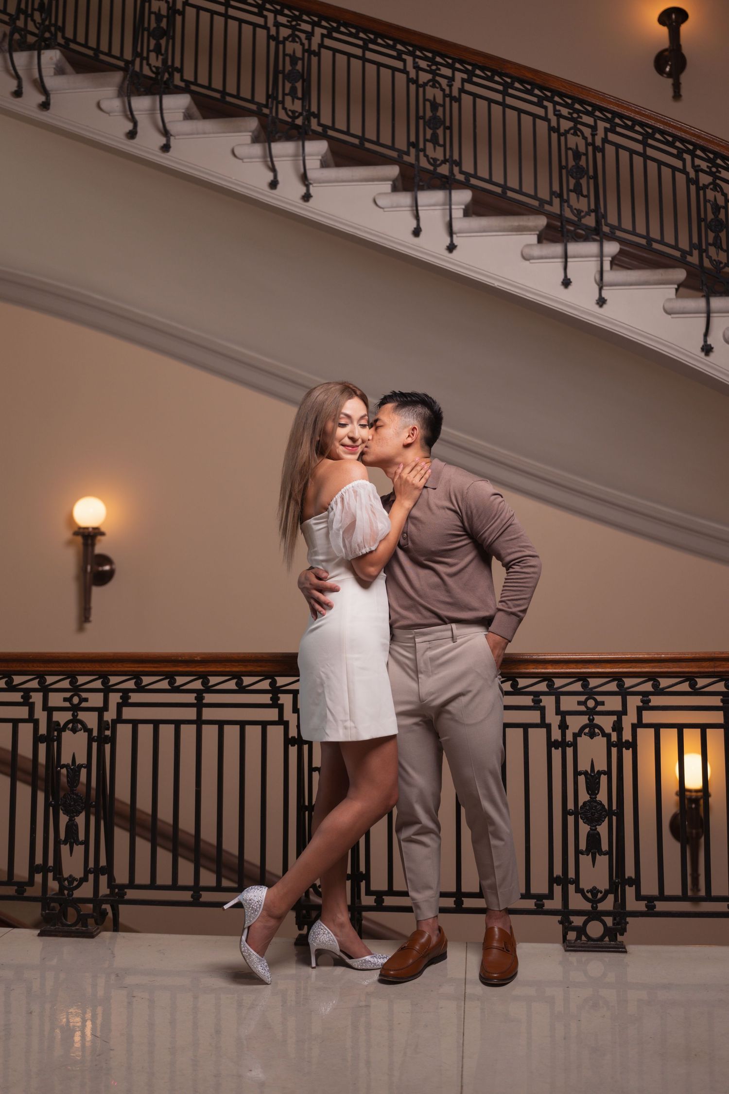 A romantic dance dip pose captured in an elegant hallway with ornate iron railings.