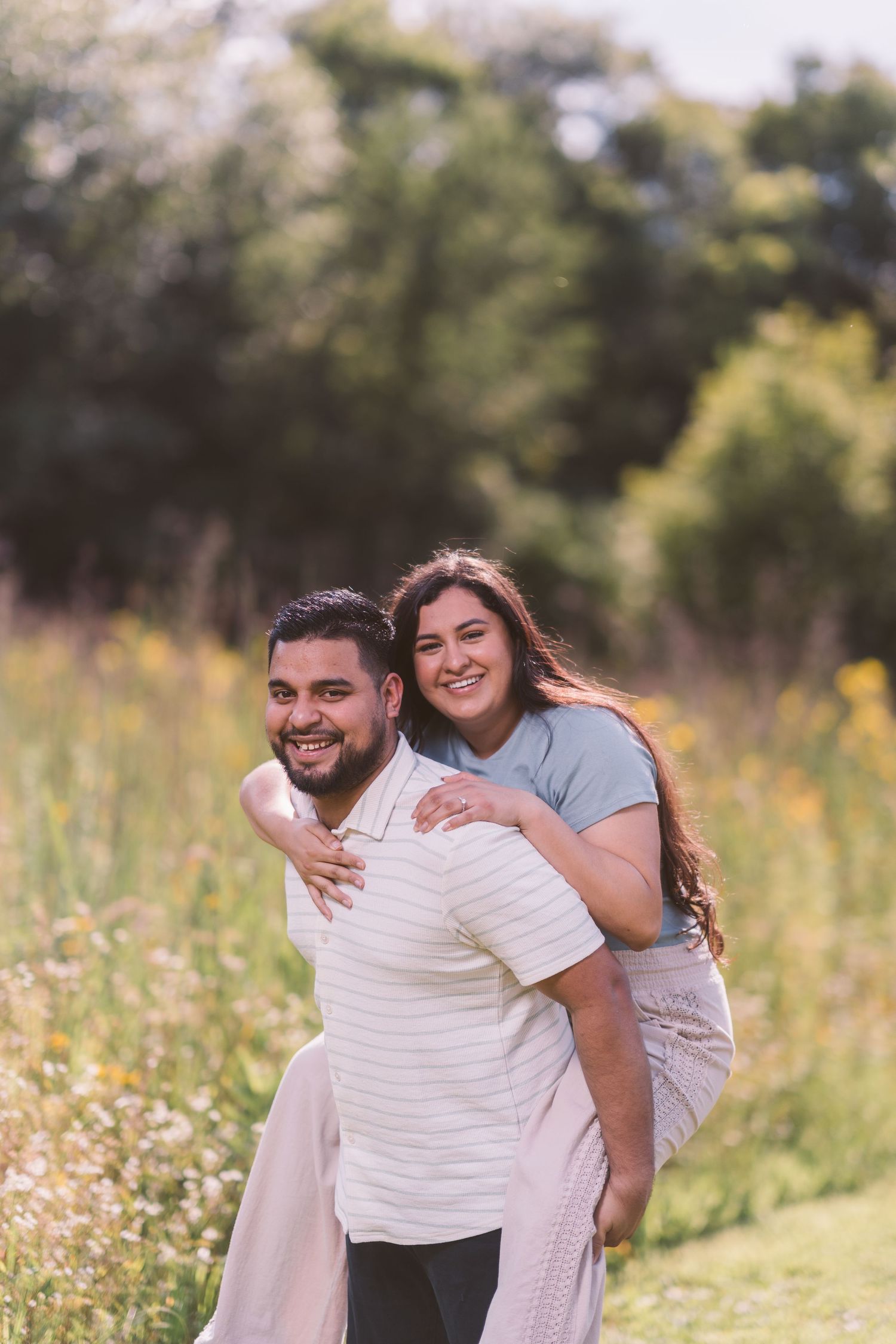 A playful piggyback ride moment captured in a summer meadow with wildflowers.