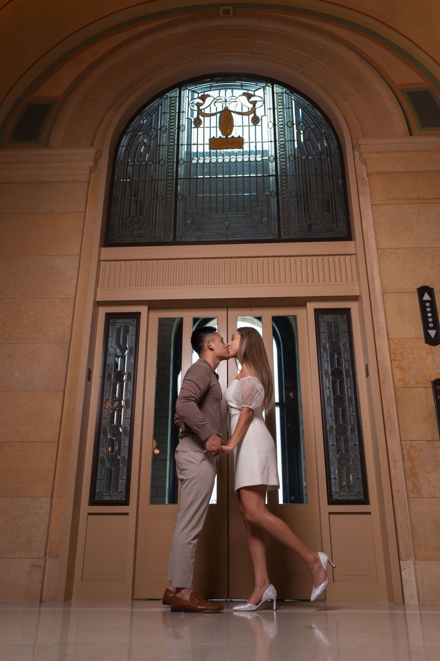 A romantic pose framed by an elegant arched doorway with stained glass windows.