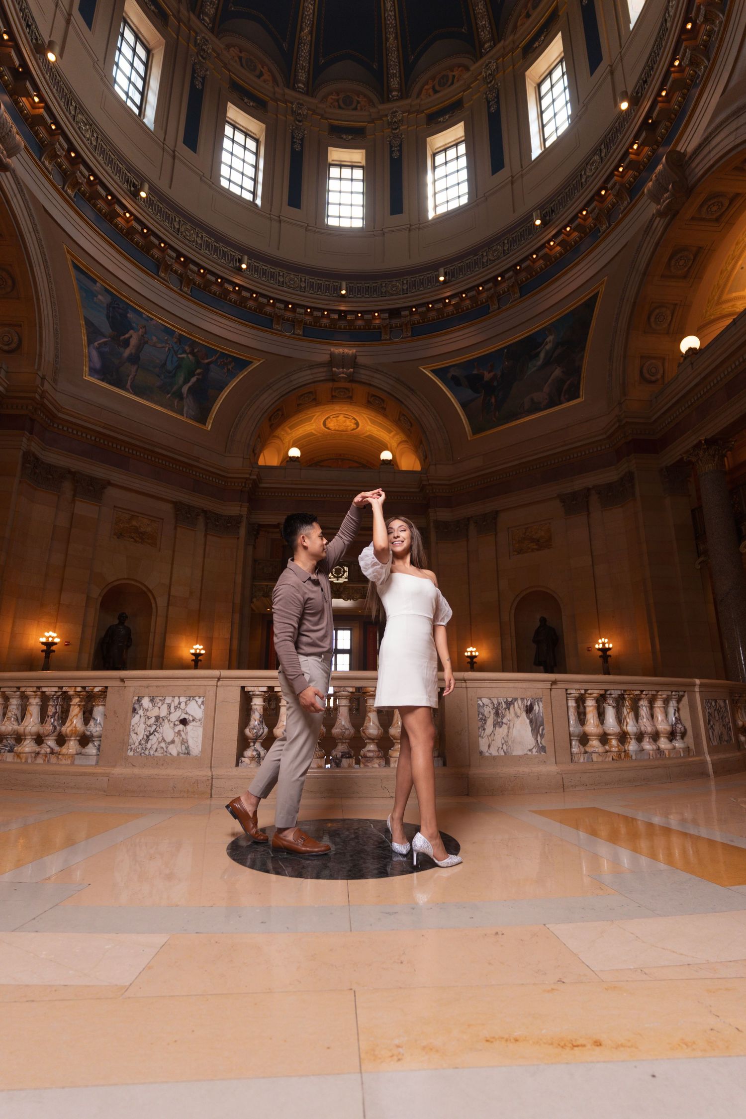 Dancing couple in a grand domed room with classical architecture and natural lighting.