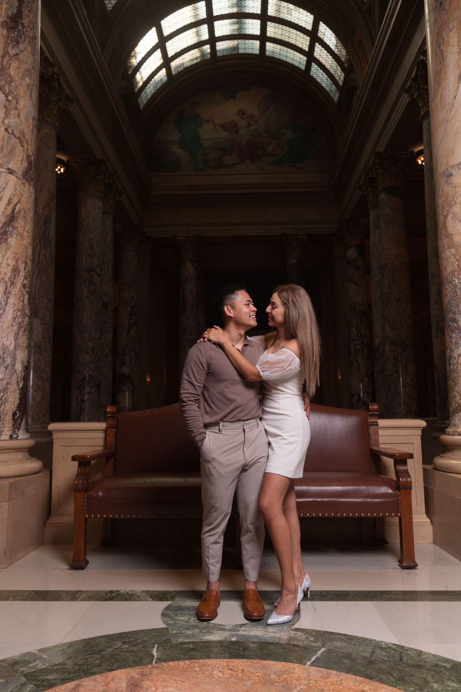 Romantic photoshoot in a marble-columned hallway with vintage furniture.