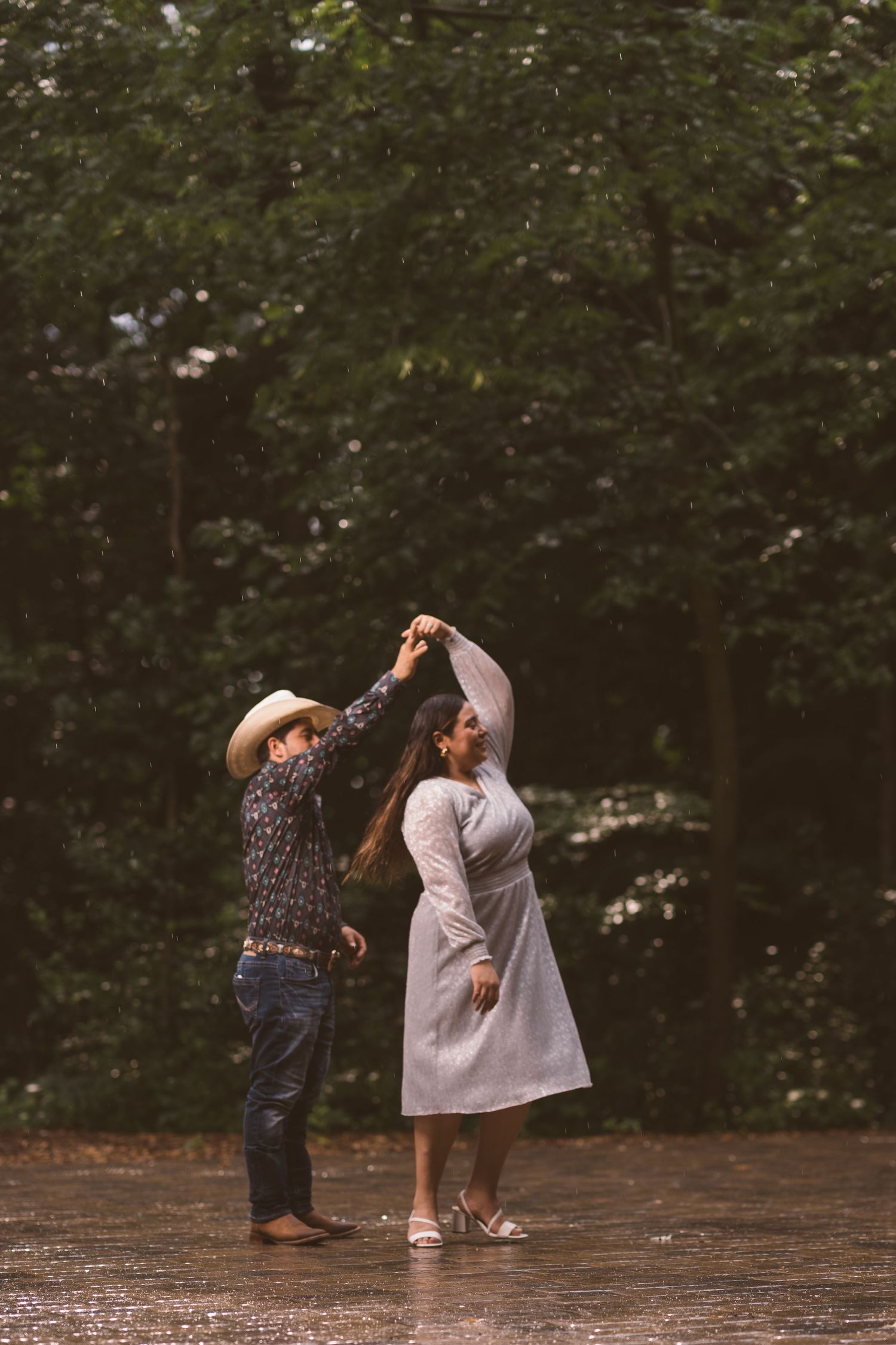 A couple dances playfully on a wet wooden deck.