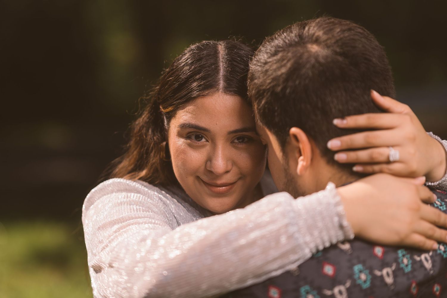 A couple shares an intimate embrace outdoors.