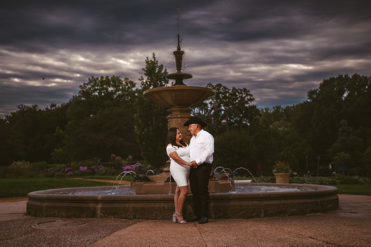 Dramatic engagement photos with stormy clouds and garden landscapes in the background.
