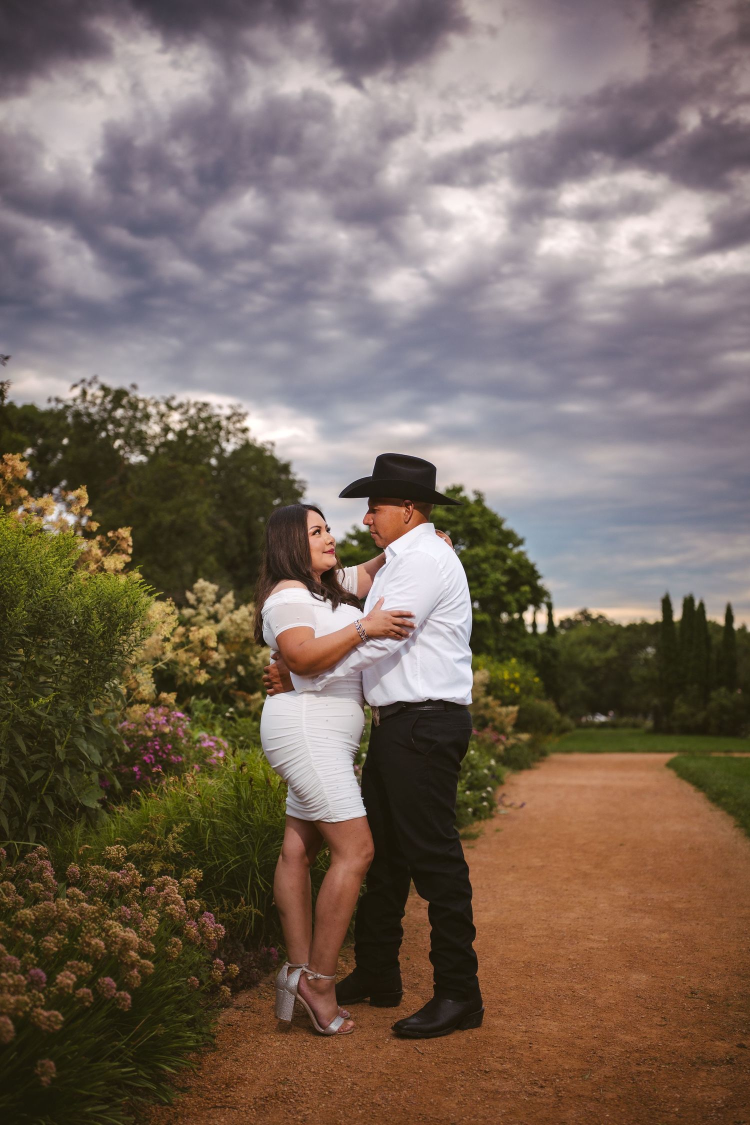 An intimate engagement session on a garden path surrounded by blooming flowers.